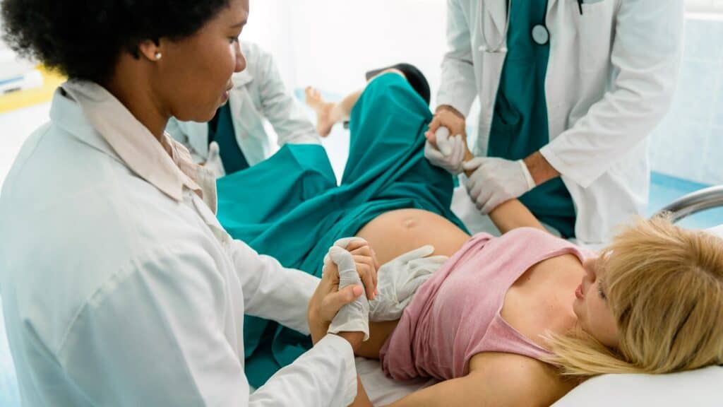 Ärztinnen und Hebammen unterstützen eine Frau bei der Geburt im Krankenhaus.