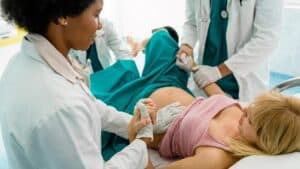 Ärztinnen und Hebammen unterstützen eine Frau bei der Geburt im Krankenhaus.