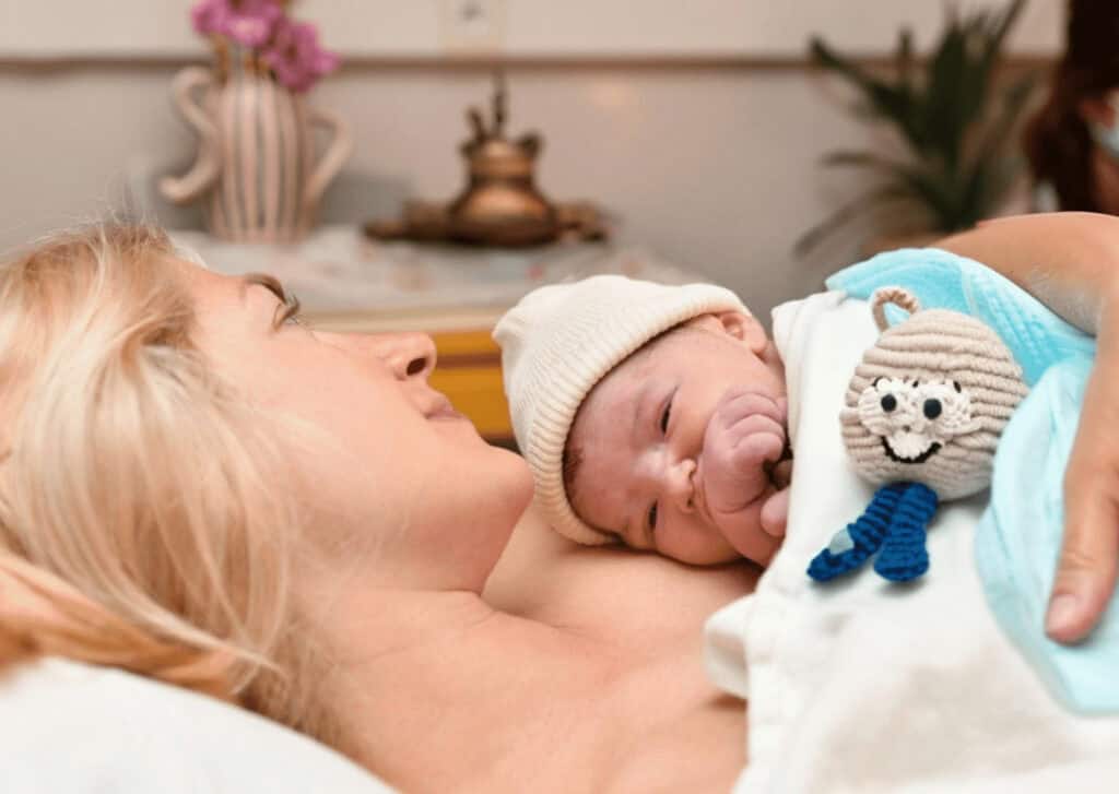 Mutter hält neugeborenes Baby mit Kuscheltier, Unterstützung bei Geburt und Elternschaft.