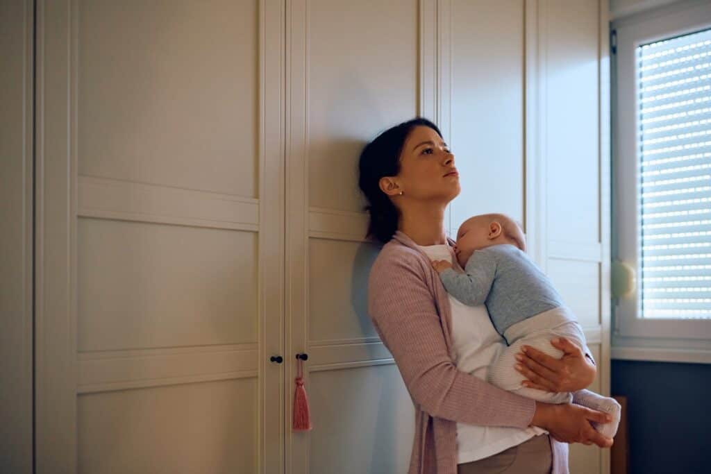 Mutter hält ihr neugeborenes Baby in den Armen, ruhend im Schlafzimmer.