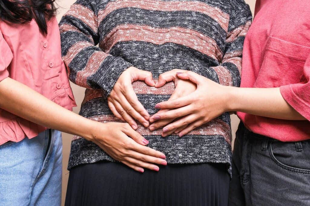 Frauen, die eine Schwangerschaft teilen, mit Händen auf Babybauch, Unterstützung bei Geburtsvorberei.