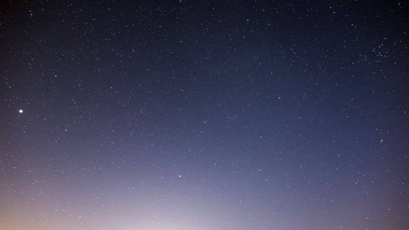 Blick auf den klaren Sternenhimmel bei Nacht, funkelnde Sterne über der Stadt.
